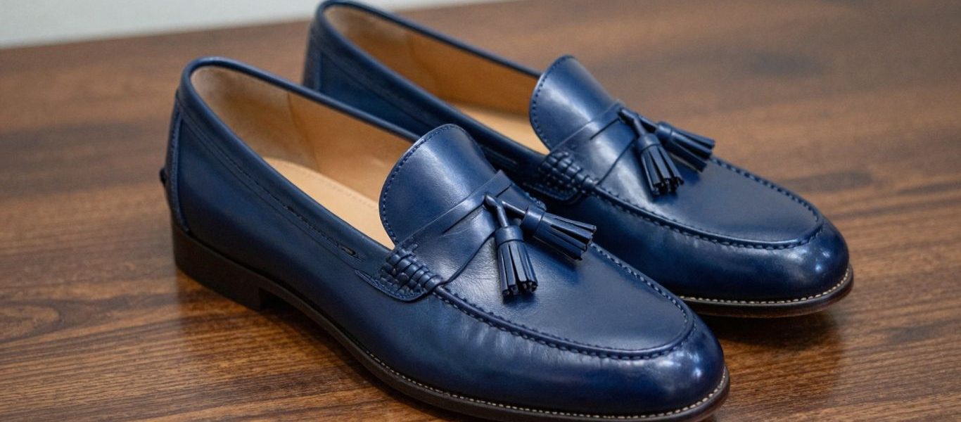 Navy tassel loafers on a polished surface.
