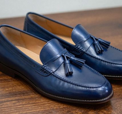Navy tassel loafers on a polished surface.