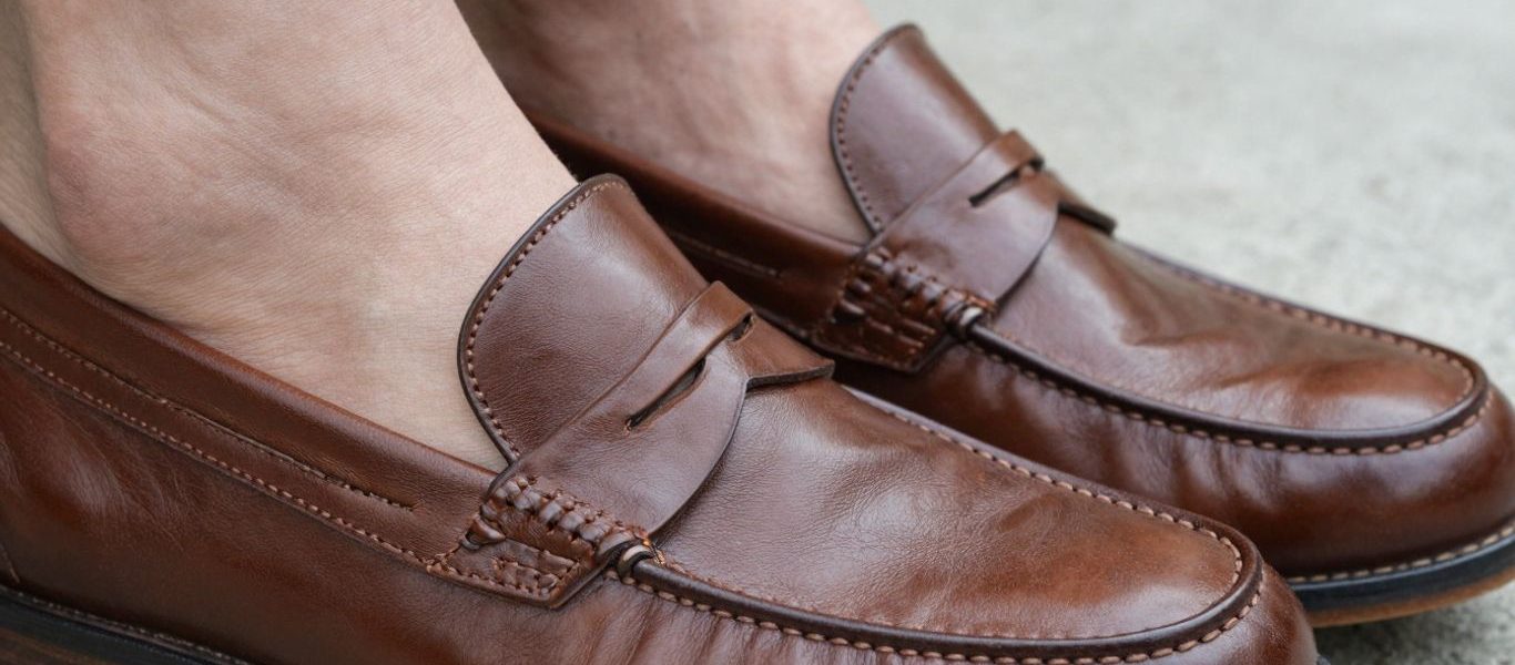 Close-up of well-fitting brown penny loafers on feet.