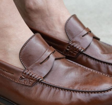 Close-up of well-fitting brown penny loafers on feet.