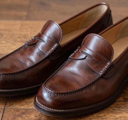 Classic brown penny loafers on a wooden floor.